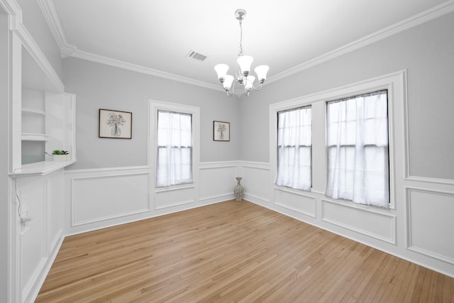 interior space with crown molding, a wealth of natural light, light hardwood / wood-style flooring, and a chandelier