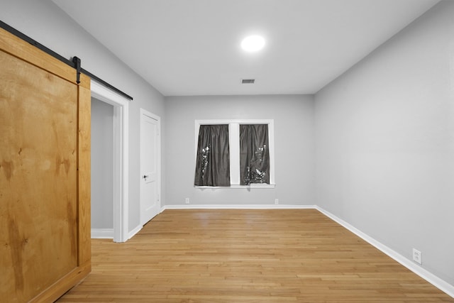 empty room with a barn door and light hardwood / wood-style flooring