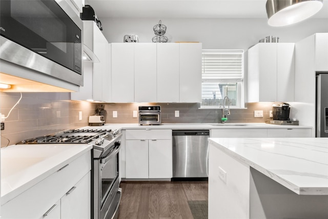 kitchen with tasteful backsplash, sink, white cabinets, and appliances with stainless steel finishes