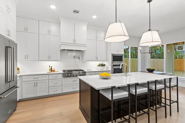 kitchen featuring white cabinets, sink, and an island with sink