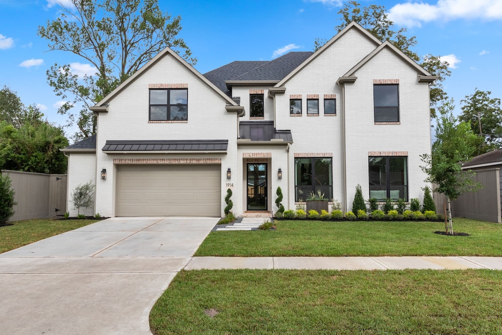 view of front of property with brick siding, concrete driveway, a standing seam roof, metal roof, and a front lawn