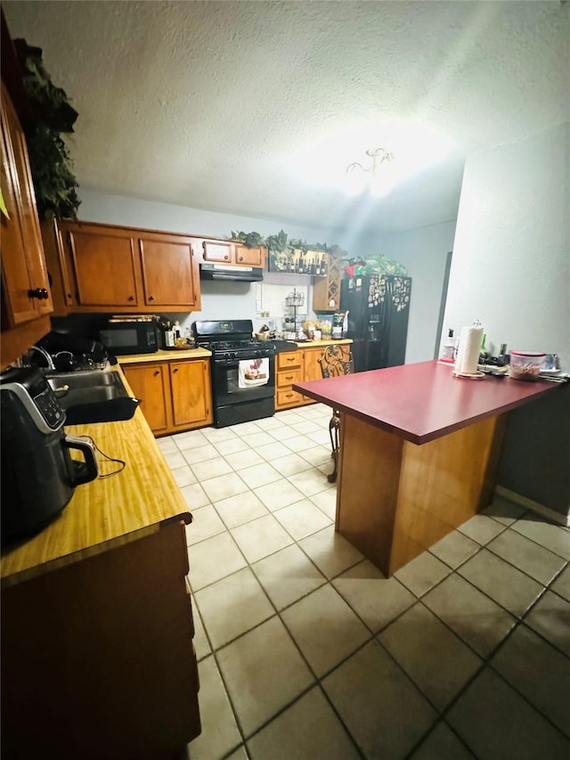 kitchen with black appliances, sink, light tile patterned floors, a textured ceiling, and kitchen peninsula