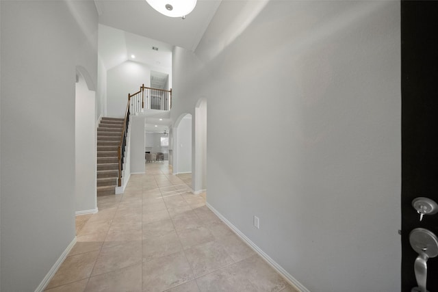 hallway featuring light tile patterned flooring and a towering ceiling