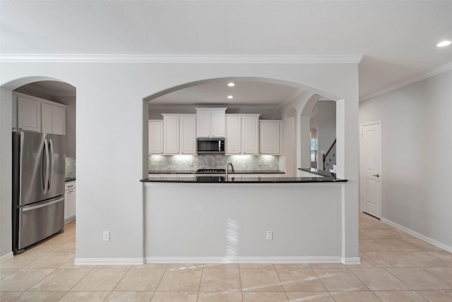 kitchen featuring ornamental molding, light tile patterned floors, tasteful backsplash, white cabinetry, and stainless steel appliances