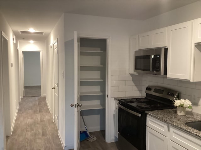 kitchen with appliances with stainless steel finishes, backsplash, light wood-type flooring, stone countertops, and white cabinets