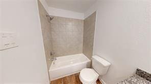 bathroom with toilet and tiled shower / bath