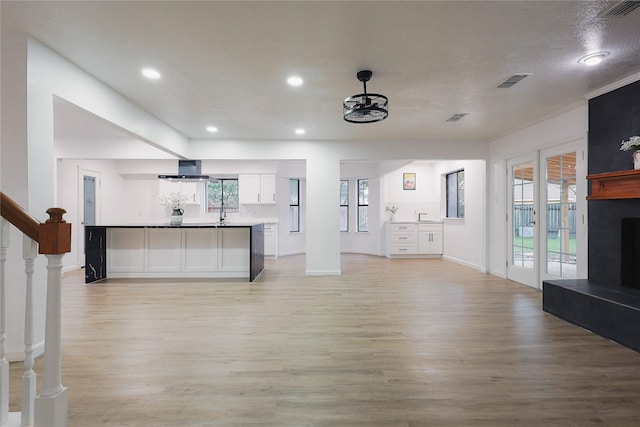 unfurnished living room featuring a tile fireplace, light hardwood / wood-style floors, and sink