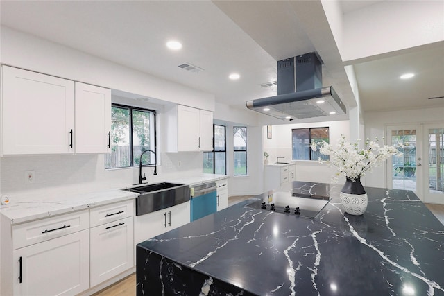 kitchen with dishwasher, stone counters, sink, island range hood, and white cabinetry