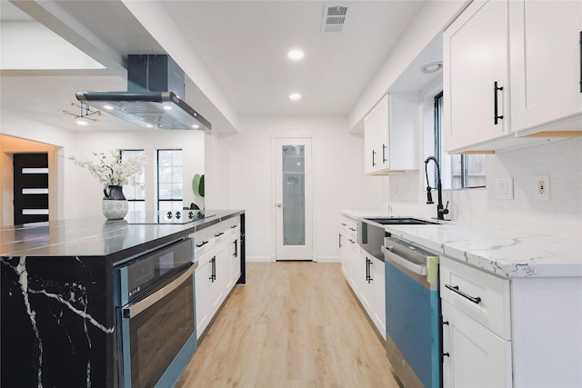 kitchen featuring light stone countertops, sink, stainless steel appliances, wall chimney range hood, and white cabinets