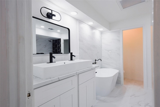 bathroom with vanity, a tub, and tile walls