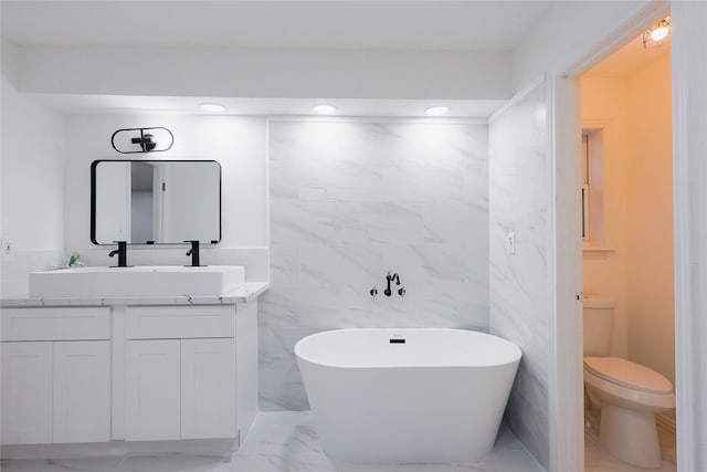 bathroom with a washtub, vanity, and toilet