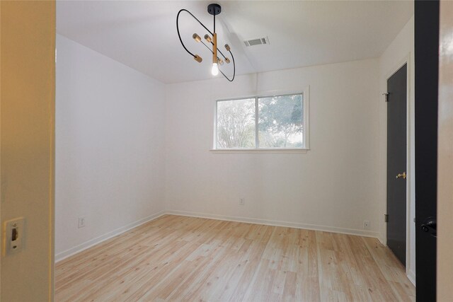 empty room with a chandelier and light hardwood / wood-style flooring