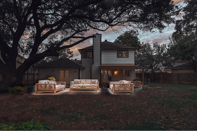 back house at dusk featuring a patio area and an outdoor living space