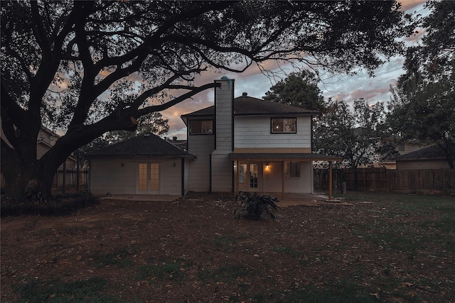 back house at dusk featuring a patio area