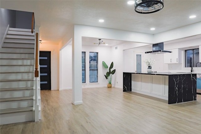 kitchen featuring white cabinetry, kitchen peninsula, a chandelier, exhaust hood, and light wood-type flooring