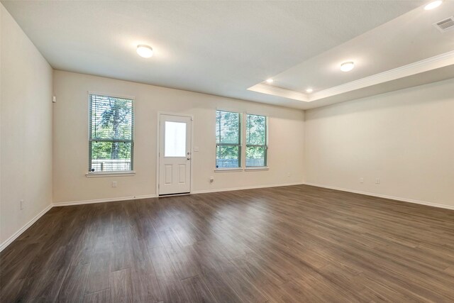 unfurnished room with a tray ceiling and dark wood-type flooring