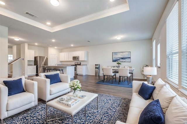 living room featuring hardwood / wood-style floors, crown molding, and a tray ceiling