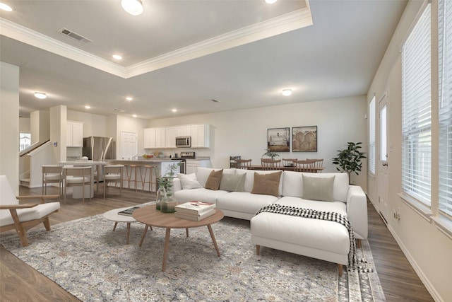 living room with ornamental molding, dark wood-type flooring, and a tray ceiling