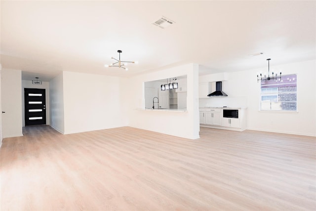 unfurnished living room featuring light hardwood / wood-style floors, sink, and a chandelier