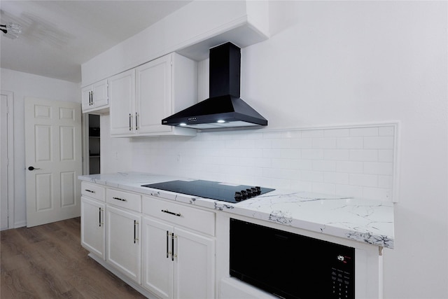 kitchen with black electric stovetop, wall chimney exhaust hood, dark hardwood / wood-style floors, light stone countertops, and white cabinetry