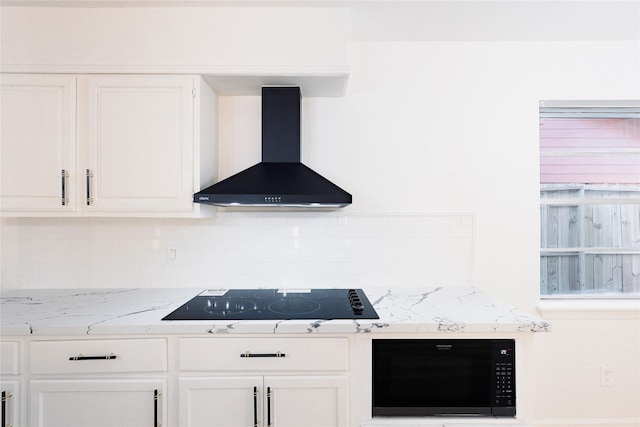 kitchen with light stone countertops, decorative backsplash, black appliances, wall chimney range hood, and white cabinetry