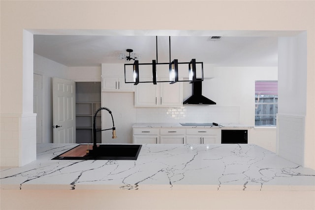 kitchen featuring white cabinets, cooktop, wall chimney range hood, and sink