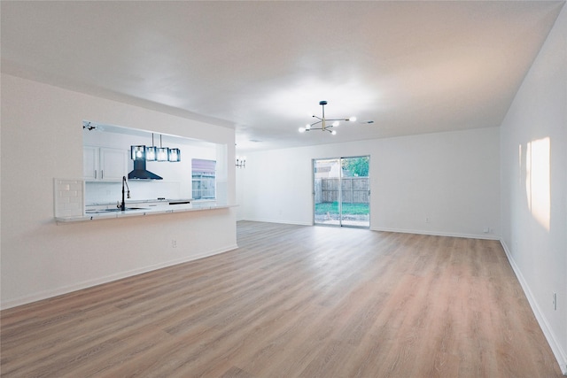 unfurnished living room with light wood-type flooring and an inviting chandelier