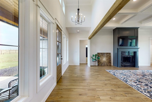 entrance foyer featuring a fireplace, beam ceiling, light hardwood / wood-style floors, and a notable chandelier