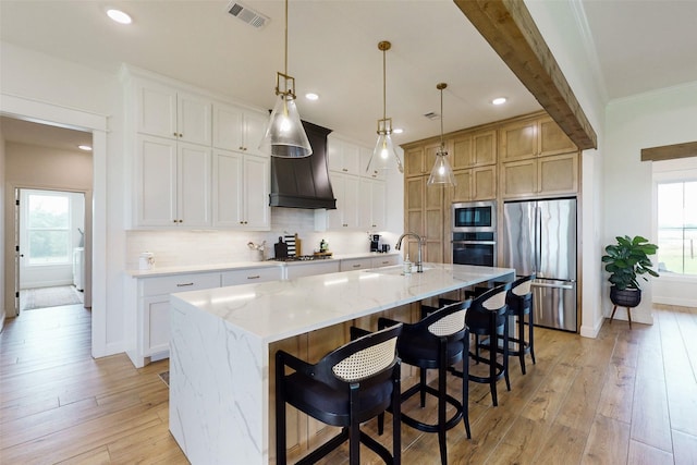 kitchen featuring decorative light fixtures, stainless steel appliances, white cabinetry, and a large island