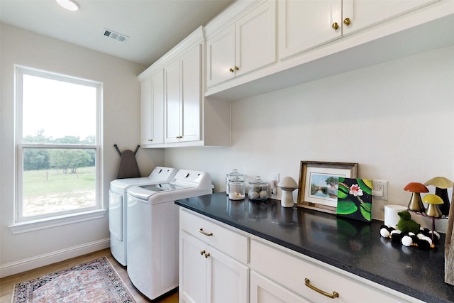 washroom featuring hardwood / wood-style floors, cabinets, and washing machine and dryer