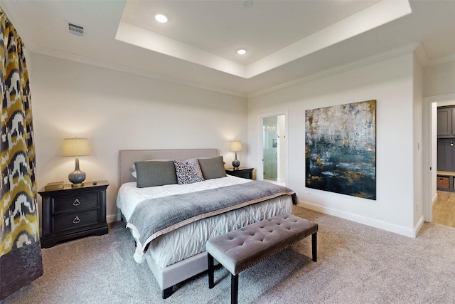 carpeted bedroom featuring a tray ceiling, ensuite bathroom, and ornamental molding