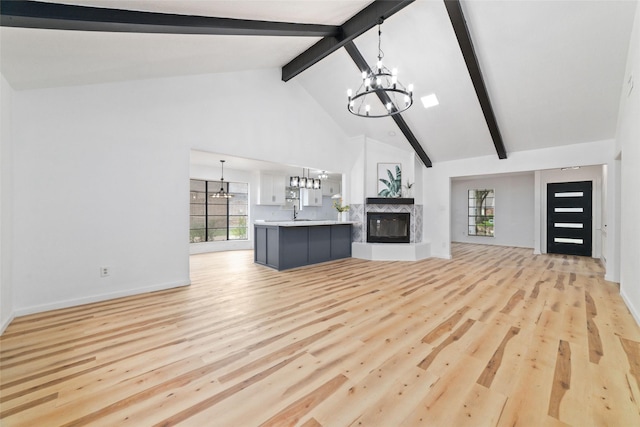 unfurnished living room with high vaulted ceiling, a high end fireplace, light hardwood / wood-style flooring, beamed ceiling, and a notable chandelier