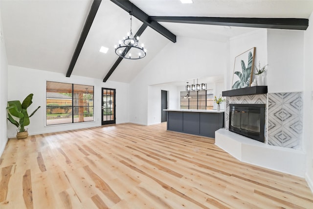 unfurnished living room featuring a chandelier, light wood-type flooring, high vaulted ceiling, and beamed ceiling