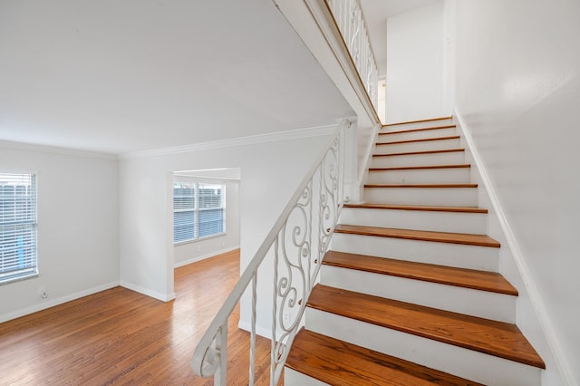 stairway with wood-type flooring and ornamental molding