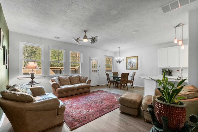 living room with ceiling fan with notable chandelier and light hardwood / wood-style flooring