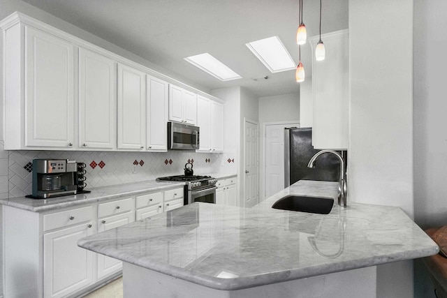 kitchen with kitchen peninsula, sink, white cabinets, and appliances with stainless steel finishes