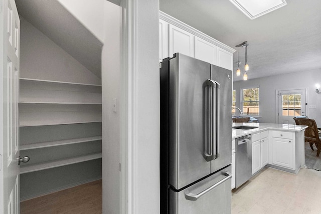 kitchen featuring sink, stainless steel appliances, kitchen peninsula, pendant lighting, and white cabinets