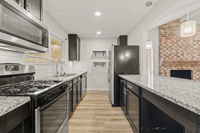 kitchen with pendant lighting, sink, light stone countertops, and stainless steel appliances