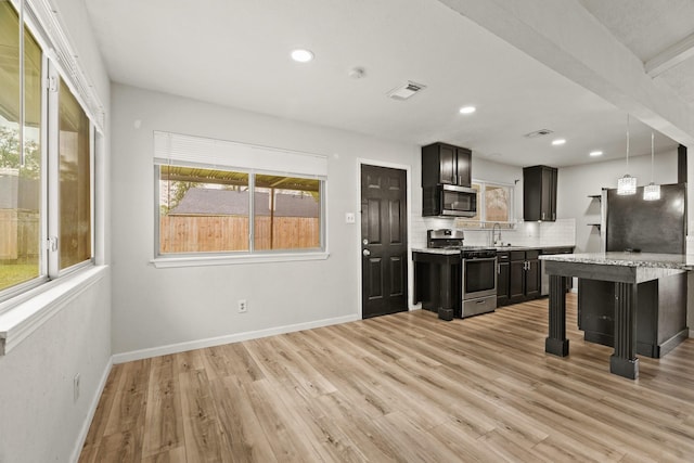 kitchen with pendant lighting, sink, a breakfast bar area, decorative backsplash, and stainless steel appliances