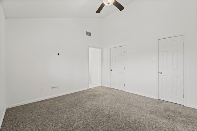 carpeted spare room featuring ceiling fan and high vaulted ceiling