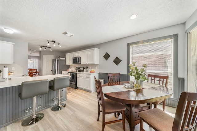 dining area with light hardwood / wood-style flooring and a textured ceiling