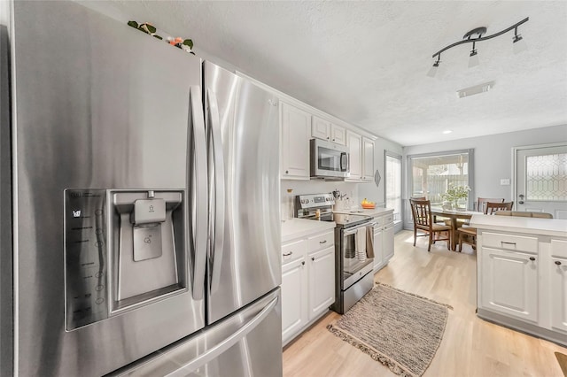 kitchen with white cabinetry, appliances with stainless steel finishes, and light hardwood / wood-style flooring