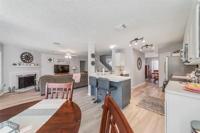 kitchen featuring white cabinetry, light hardwood / wood-style flooring, and a textured ceiling