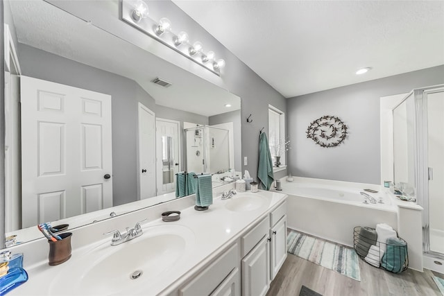 bathroom with hardwood / wood-style floors, vanity, and shower with separate bathtub