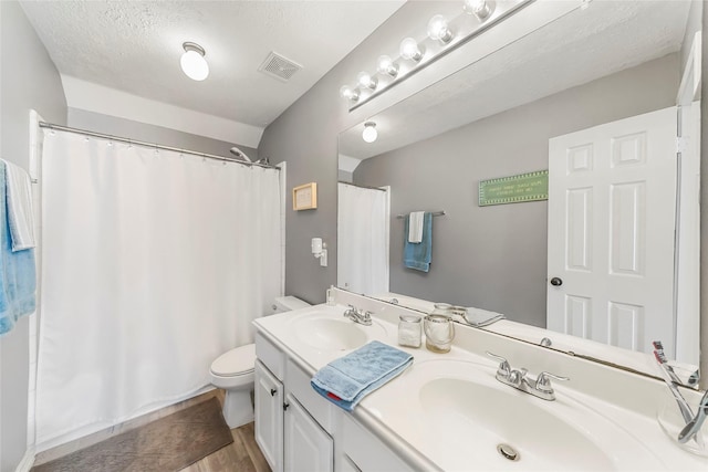 bathroom featuring hardwood / wood-style floors, vanity, a shower with shower curtain, toilet, and a textured ceiling