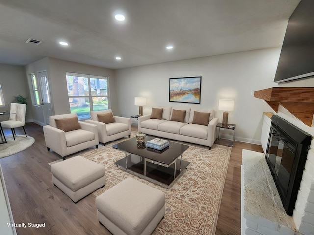 living room with a brick fireplace and hardwood / wood-style floors