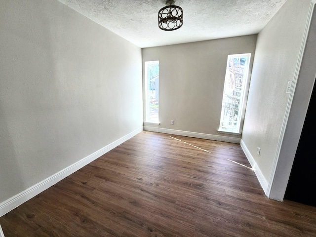 unfurnished room with a textured ceiling and dark hardwood / wood-style floors