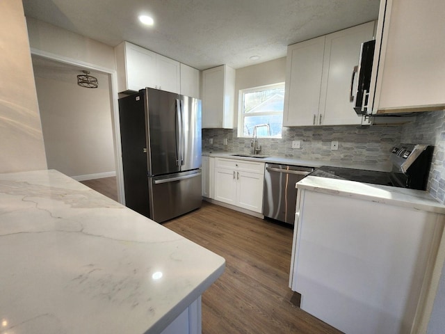 kitchen with stainless steel appliances, dark hardwood / wood-style flooring, white cabinets, and light stone counters