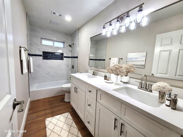 full bathroom featuring toilet, tiled shower / bath, wood-type flooring, and vanity