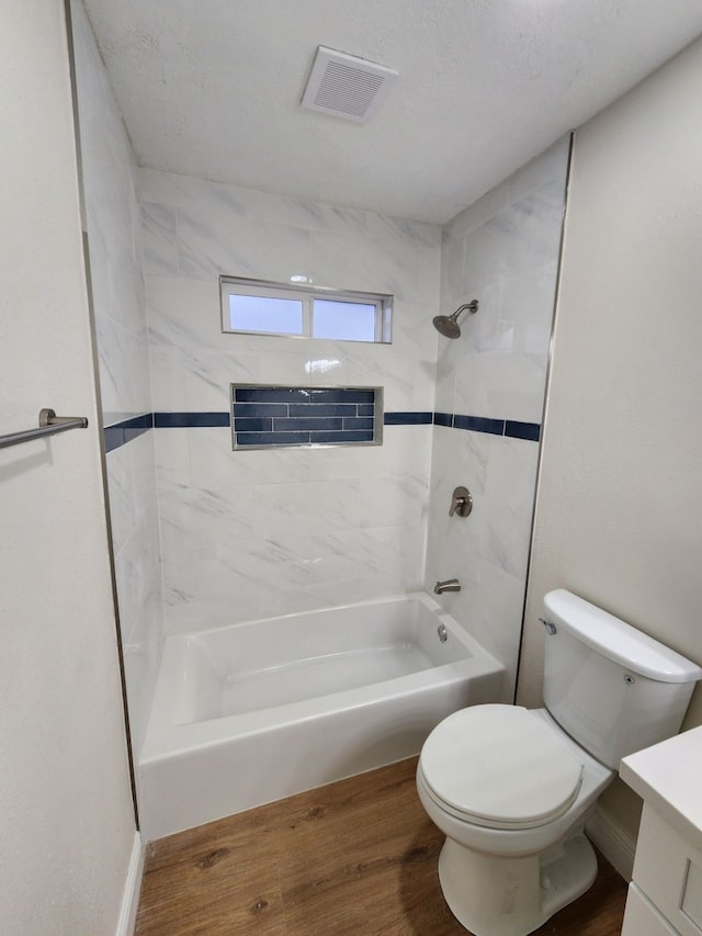 full bathroom with toilet, tiled shower / bath, vanity, and hardwood / wood-style floors